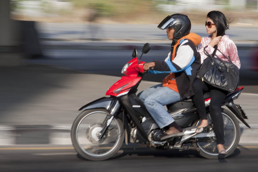 woman riding a Bangkok motorcycle taxi to work