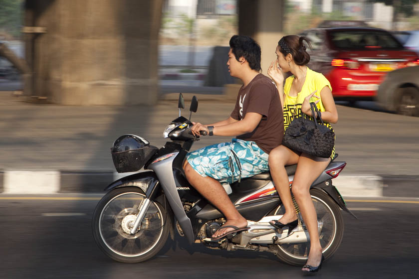woman with geogeous thighs and short skirt  rides on Bangkok motorcycle